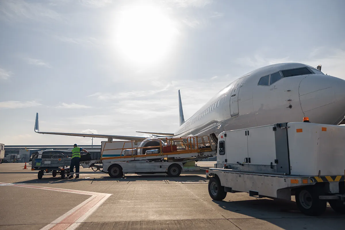 worker-loading-baggage-on-conveyor-belt-to-an-airp-2024-10-18-08-07-44-utc